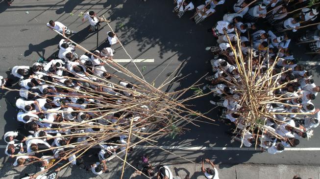 Seorang pemuda berdiri di atas tongkat yang disatukan warga saat Tradisi Mekotek di Desa Munggu, Badung, Bali, Sabtu (5/1). ANTARA FOTO/Fikri Yusuf