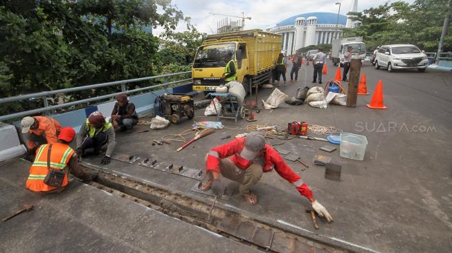 Petugas melakukan perbaikan Jembatan layangnyang renggang di Jalan Layang, Jalan Industri Raya, Kemayoran, Jakarta Pusat, Minggu (6/1). [Suara.com/Muhaimin A Untung] 