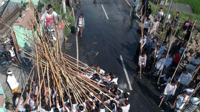 Seorang pemuda berdiri di atas tongkat yang disatukan warga saat Tradisi Mekotek di Desa Munggu, Badung, Bali, Sabtu (5/1). ANTARA FOTO/Fikri Yusuf