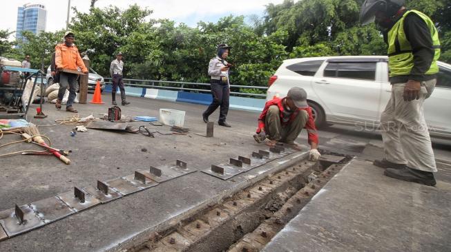 Petugas melakukan perbaikan Jembatan layangnyang renggang di Jalan Layang, Jalan Industri Raya, Kemayoran, Jakarta Pusat, Minggu (6/1). [Suara.com/Muhaimin A Untung] 