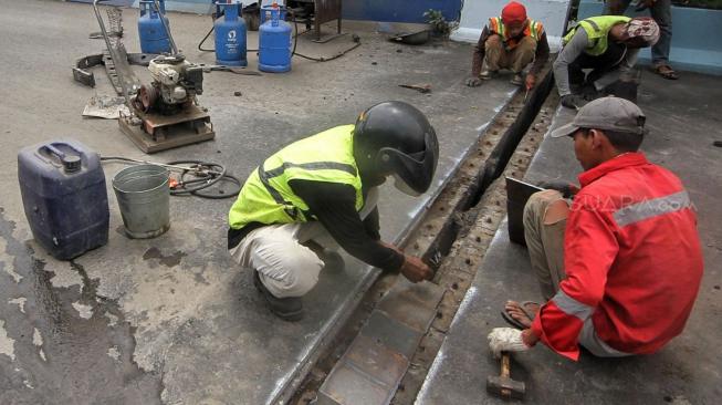 Petugas melakukan perbaikan Jembatan layangnyang renggang di Jalan Layang, Jalan Industri Raya, Kemayoran, Jakarta Pusat, Minggu (6/1). [Suara.com/Muhaimin A Untung] 