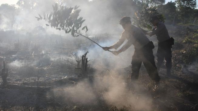 Personil Kepolisian Polres Aceh Barat bersama warga memadamkan api yang membakar lahan gambut dengan cara manual di Kawasan Desa Seuneubok, Kecamatan Johan Pahlawan, Aceh Barat, Aceh, Minggu (6/1). ANTARA FOTO/Syifa Yulinnas
