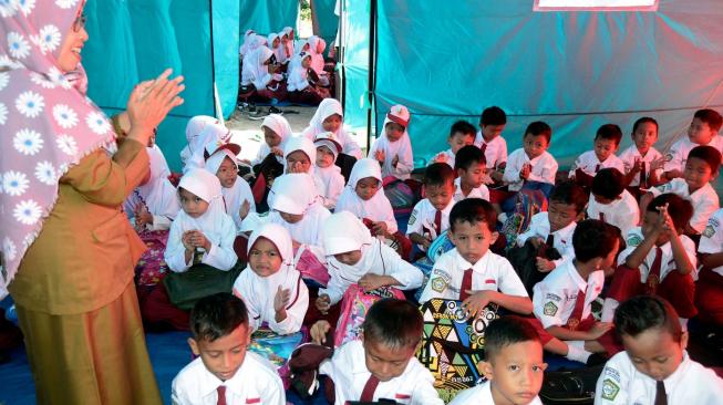 Siswa SD Yayasan Madrasah Ibtidaiyah (MI) Darussalam Sukaraja mengikuti kegiatan belajar mengajar dalam tenda darurat di Desa Sukaraja, Kabupaten Lampung Selatan, Lampung, Senin (7/1). ANTARA FOTO/Ardiansyah