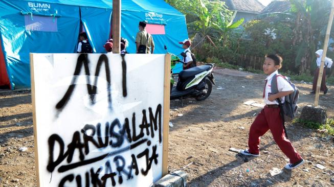 Siswa SD Yayasan Madrasah Ibtidaiyah (MI) Darussalam Sukaraja datang ke sekolah yang menggunakan tenda darurat di Desa Sukaraja, Kabupaten Lampung Selatan, Lampung, Senin (7/1). ANTARA FOTO/Ardiansyah