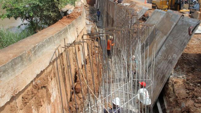 Perbaikan tanggul sungai dan jalan yang amblas di perumahan Kawasan Kemang Pratama, Bekasi, Jawa Barat, Selasa (8/1). [Suara.com/Fakhri Hermansyah]