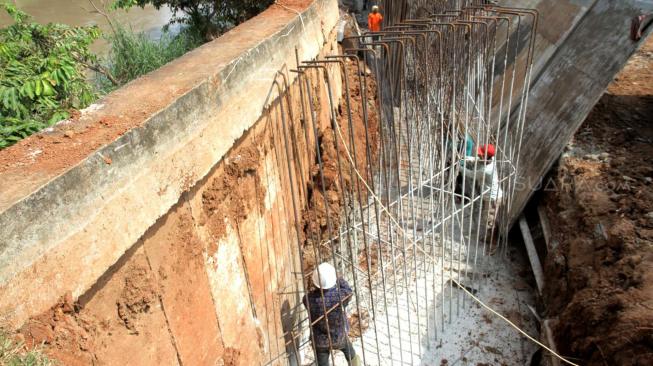 Perbaikan tanggul sungai dan jalan yang amblas di perumahan Kawasan Kemang Pratama, Bekasi, Jawa Barat, Selasa (8/1). [Suara.com/Fakhri Hermansyah]