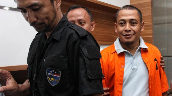 Polisi menggiring Bagus Bawana Putra, tersangka kasus berita hoax saat Rilis berita hoax 7 kontainer surat suara tercoblos di Divisi Humas, Mabes Polri, Jakarta, Rabu (9/1). [Suara.com/Muhaimin A Untung]