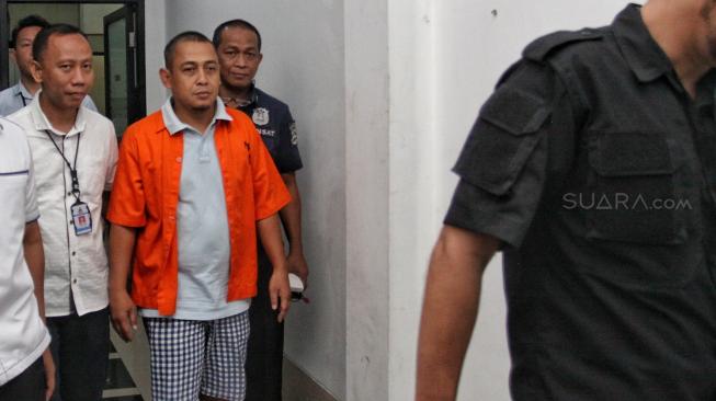 Polisi menggiring Bagus Bawana Putra, tersangka kasus berita hoax saat Rilis berita hoax 7 kontainer surat suara tercoblos di Divisi Humas, Mabes Polri, Jakarta, Rabu (9/1). [Suara.com/Muhaimin A Untung]