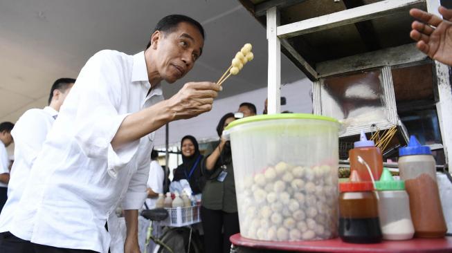 Presiden Joko Widodo membeli jajanan Cilok saat meninjau Program Mekaar binaan PNM di Lapangan Sepak Bola Gongseng, Jakarta Timur, Kamis (10/1).  [ANTARA FOTO/Puspa Perwitasari]