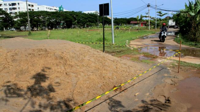 Warga beraktifitas di sekitaran gundukan tanah yang diduga tercemar limbah B3 kawasan Marunda, Jakarta Utara, Sabtu (12/1). [Suara.com/Fakhri Hermansyah]
