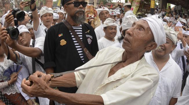 Seorang umat Hindu yang kesurupan menusukkan keris ke tubuhnya saat Tradisi Ngerebong di Pura Dalem Pengrebongan, Denpasar, Bali, Minggu (13/1). [ANTARA FOTO/Fikri Yusuf]