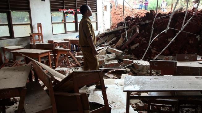 Seorang guru melihat ruang kelas dan ruang laboratorium komputer yang hancur tertimpa truk di SDN Bambu Apus 1 Pamulang, Tangerang Selatan, Banten, Senin (14/1).  [ANTARA FOTO/Muhammad Iqbal]