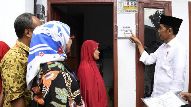 Presiden Joko Widodo (kanan) berbincang dengan penerima fasilitas pemasangan listrik gratis di Kampung Pasar Kolot, Garut, Jawa Barat, Jumat (18/1). [ANTARA FOTO/Puspa Perwitasari]