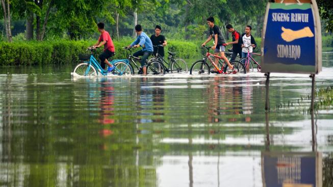 Seorang anak melintas di Jalan Raya yang terendam banjir di Porong, Sidoarjo, Jawa Timur, Sabtu (19/1/). [ANTARA FOTO/Umarul Faruq]