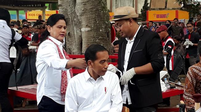 Presiden Joko Widodo didampingi Ibu Negara Iriana Joko Widodo saat mengikuti potong rambut massal di area wisata Situ Bagendit, Garut, Jawa Barat, Sabtu (19/1). [Suara.com/Ummi Hadyah Saleh]