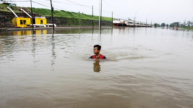 Seorang anak melintas di Jalan Raya yang terendam banjir di Porong, Sidoarjo, Jawa Timur, Sabtu (19/1/). [ANTARA FOTO/Umarul Faruq]
