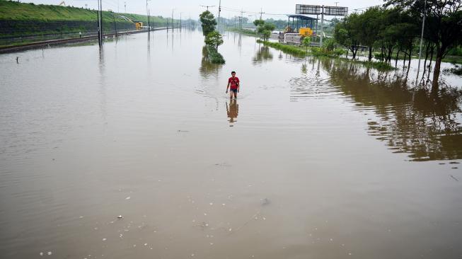 Warga melintas di Jalan Raya yang terendam banjir di Porong, Sidoarjo, Jawa Timur, Sabtu (19/1). [ANTARA FOTO/Umarul Faruq]