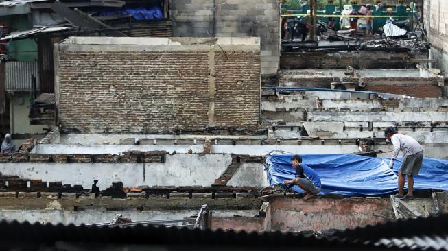 Warga berada di area rumahnya yang terdampak kebakaran di kawasan Tomang Utara, Jakarta, Senin (21/1). [Suara.com/Muhaimin A Untung]