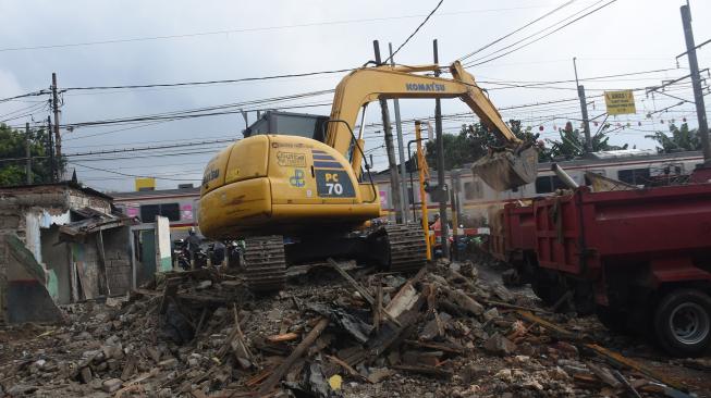 Petugas Dinas Bina Marga DKI Jakarta menggunakan alat berat saat membongkar rumah yang telah dibebaskan lahannya di jalur sejajar rel kawasan Rawajati, Jakarta Selatan, Senin (21/1/2019).  [ANTARA FOTO/Indrianto Eko Suwarso]