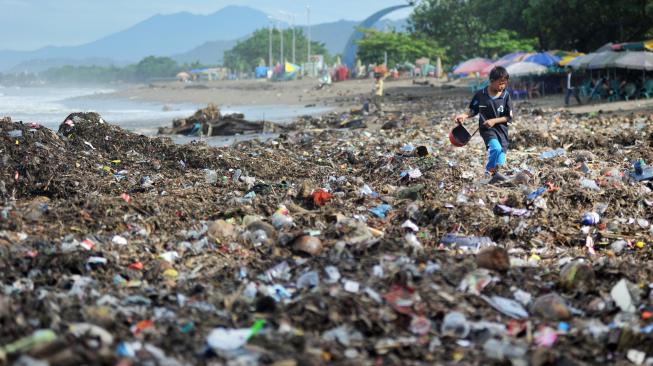 Seorang anak berjalan di atas tumpukan sampah plastik yang berserakan di Pantai Padang, Sumatera Barat, Selasa (22/1). [ANTARA FOTO/Iggoy el Fitra]