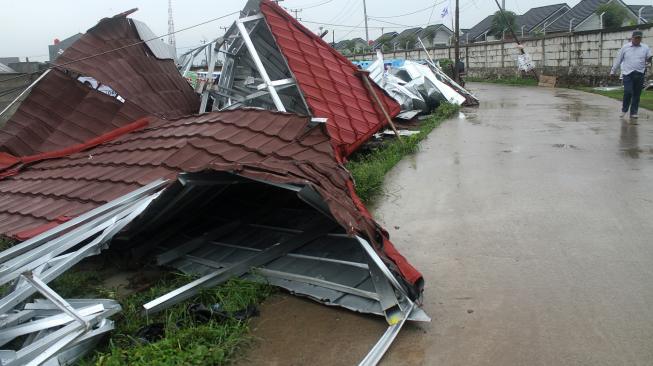 Warga melintas di dekat rumah yang rusak akibat diterjang angin puting beliung di kawasan Jejalen, Bekasi, Jawa Barat, Selasa (22/1). [ANTARA FOTO/Risky Andrianto]