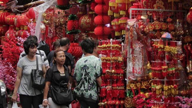 Seorang pembeli memilah pernak-pernik imlek di salah satu toko di Glodok, Jakarta Barat, Selasa (22/1).[Suara.com/Muhaimin A Untung]