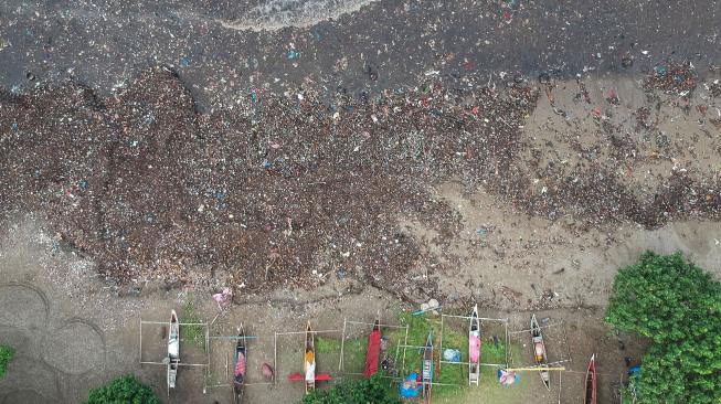 Perahu nelayan terhambat tumpukan sampah plastik yang berserakan di Pantai Padang, Sumatera Barat, Selasa (22/1).[ANTARA FOTO/Iggoy el Fitra]