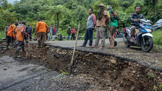 Sejumlah pekerja memperbaiki jalan yang ambles di Desa Tenogo, Paninggaran, Kabupaten Pekalongan, Jawa Tengah, Rabu (23/1). [ANTARA FOTO/Harviyan Perdana Putra]