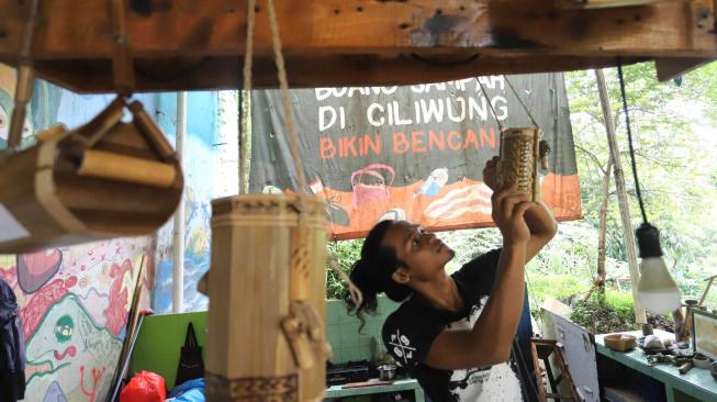 Anggota Komunitas Ciliwung Depok (KCD)  saat membuat kerajinan tangan dengan menggunakan bambu bekas di sekitar kawasan bantaran Sungai Ciliwung, Depok Jawa Barat, Jum'at (25/1). [Suara.com/Fakhri Hermansyah]