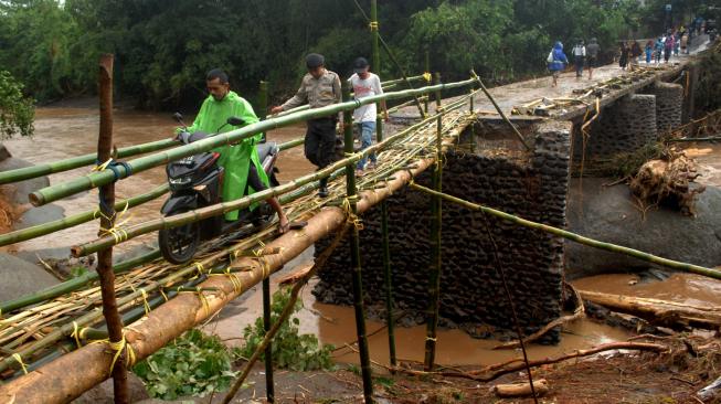 Warga melewati jembatan darurat sementara yang terbuat dari bambu di desa Pallatikang, Kabupaten Gowa, Sulawesi Selatan, Kamis (24/1). ANTARA FOTO/Abriawan Abhe