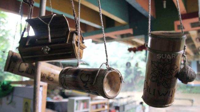 Anggota Komunitas Ciliwung Depok (KCD)  saat membuat kerajinan tangan dengan menggunakan bambu bekas di sekitar kawasan bantaran Sungai Ciliwung, Depok Jawa Barat, Jum'at (25/1). [Suara.com/Fakhri Hermansyah]