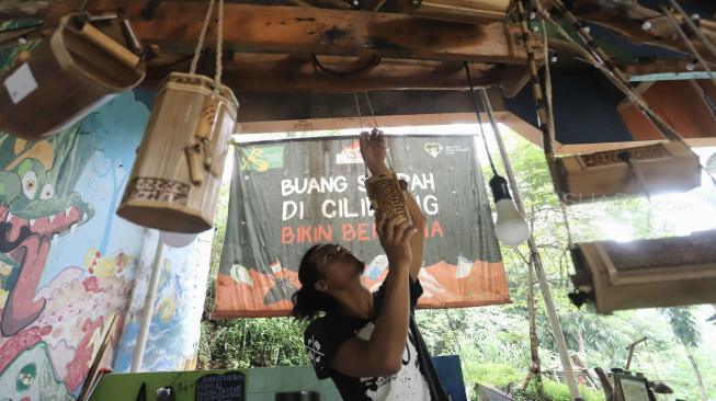 Anggota Komunitas Ciliwung Depok (KCD)  saat membuat kerajinan tangan dengan menggunakan bambu bekas di sekitar kawasan bantaran Sungai Ciliwung, Depok Jawa Barat, Jum'at (25/1). [Suara.com/Fakhri Hermansyah]