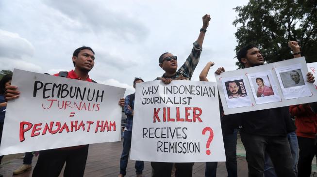 Sejumlah jurnalis membentangkan spanduk dan poster saat menggelar aksi tolak remisi pembunuh jurnalis di Taman Aspirasi, Jakarta, Jumat (25/1). [Suara.com/Muhaimin A Untung]