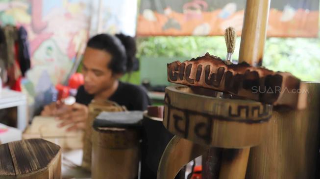 Anggota Komunitas Ciliwung Depok (KCD)  saat membuat kerajinan tangan dengan menggunakan bambu bekas di sekitar kawasan bantaran Sungai Ciliwung, Depok Jawa Barat, Jum'at (25/1). [Suara.com/Fakhri Hermansyah]