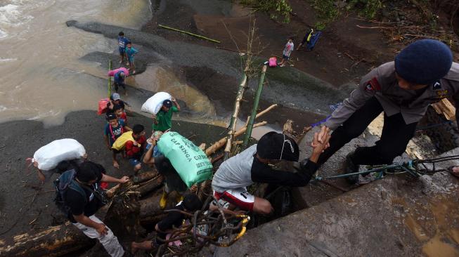 Polisi berusaha membantu warga menaiki jembatan saat mengungsi akibat longsor di Desa Pattilasang, Kecamatan Manuju, Gowa, Sulawesi Selatan, Jumat (25/1). ANTARA FOTO/Yusran Uccang