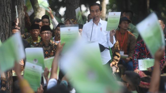 Presiden Joko Widodo menunjukkan Surat Keputusan tentang Pengelolaan Hutan Sosial saat berpidato di Wana Wisata Pokland Haurwangi, Cianjur, Jumat (8/2). [ANTARA FOTO/Akbar Nugroho Gumay]