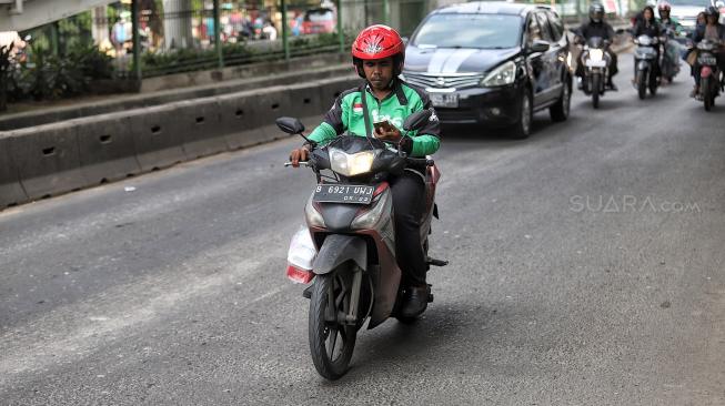 Pengendara sepeda motor menggunakan aplikasi GPS (pelacak jalan) saat berkendara di kawasan manggarai, Jakarta, Jumat (8/2). [Suara.com/Muhaimin A Untung]