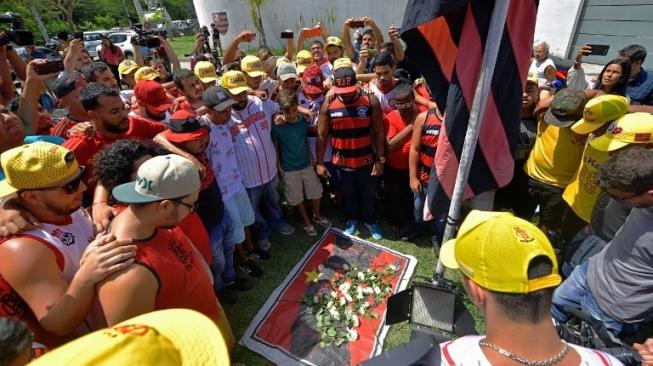 Para suporter klub Flamengo menaruh bunga di depan asrama pusat latihan tim muda yang terbakar sehingga menewaskan 10 pemain mudanya di Rio de Janeiro pada Jumat (8/2/2019) pagi waktu setempat. CARL DE SOUZA / AFP