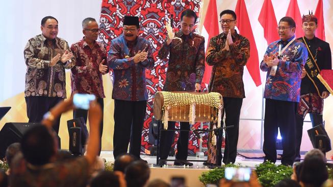 Presiden Joko Widodo (keempat kiri) didampingi Ketua Dewan Pers Yosep Adi Prasetyo (kelima kiri), Menteri Komunikasi dan Informatika Rudiantara (keenam kiri), Gubernur Jawa Timur Soekarwo (ketiga kiri) dan Ketua PWI Atal Sembiring Depari (kedua kiri) serta Penanggung Jawab HPN 2019 Margiono (kiri) memukul tongtong alat musik Madura saat puncak perayaan Hari Pers Nasional (HPN) di Surabaya, Jawa Timur, Sabtu (9/2/2019). Perayaan HPN 2019 tersebut mengangkat tema 'Pers Menguatkan Ekonomi Kerakyatan Berbasis Digital'. [ANTARA FOTO/Zabur Karuru]