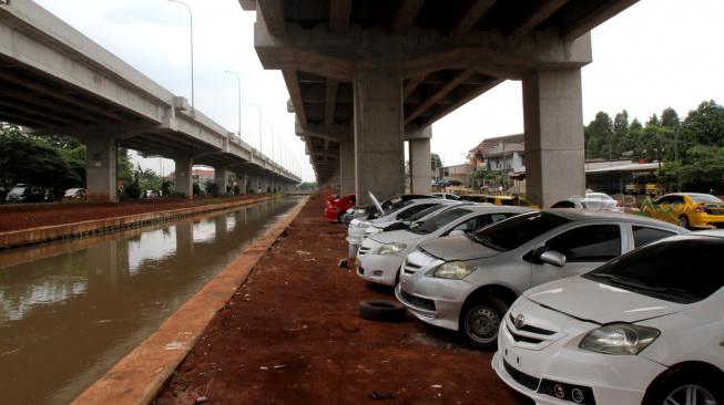 Sejumlah mobil terparkir di bawah kolong tol Becakayu Kalimalang, Jakarta Timur, Sabtu (9/2). [Suara.com/Fakhri Hermansyah]