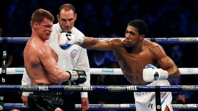 Petinju Inggris, Anthony Joshua (kanan), mendaratkan hook kanan yang bersarang telak di area wajah penantangnya, Alexander Povetkin (Rusia), dalam duel di Stadion Wembley, London, Inggris, Sabtu (22/9/2018). [AFP/Adrian Dennis]