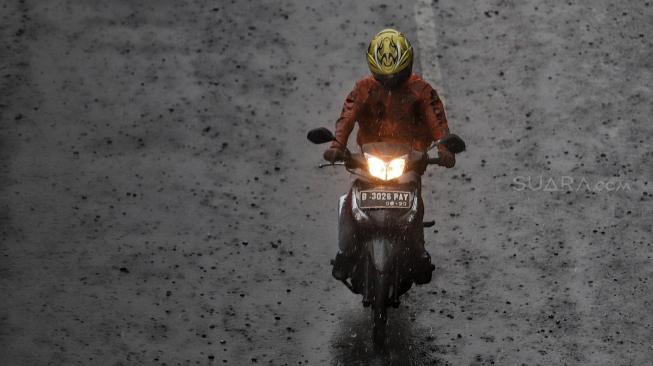 Pengendara meliintasi hujan di kawasan Gatot Subroto, Jakarta, Senin (11/2). [Suara.com/Muhaimin A Untung]