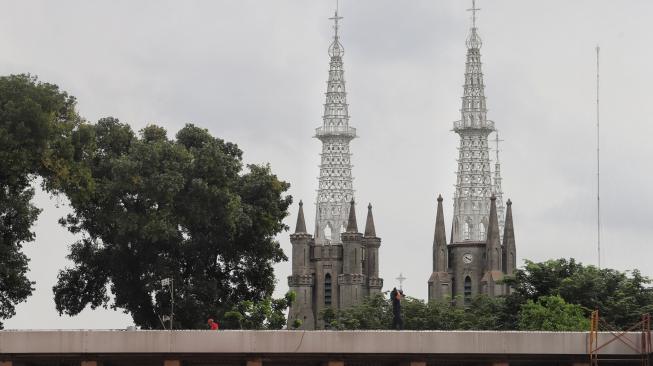 Sejumlah petugas Damkar membersihkan Gereja Katedral dan Masjid Istiqlal di Jakarta, Selasa (12/2). [Suara.com/Muhaimin A Untung]