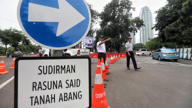 Petugas mengatur lalu lintas saat diadakan uji coba sistem satu arah di Dukuh Bawah, Setiabudi, Jakarta Selatan, Rabu (13/2). [Suara.com/Muhaimin A Untung]