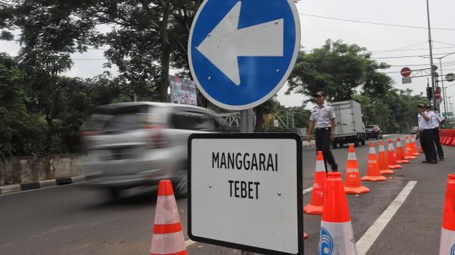 Petugas mengatur lalu lintas saat diadakan uji coba sistem satu arah di Dukuh Bawah, Setiabudi, Jakarta Selatan, Rabu (13/2). [Suara.com/Muhaimin A Untung]