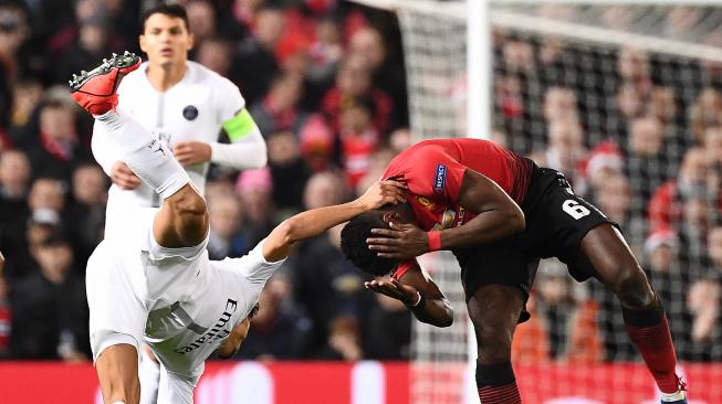 Bek Paris Saint Germain Marquinhos (kiri) melakukan pelanggaran terhadap pemain tengah Manchester United Paul Pogba pada pertandingan leg pertama babak 16 besar Liga Champions antara Manchester United melawan Paris Saint Germain (PSG) di Old Trafford, Manchester, Inggris, Rabu (13/2) dini hari WIB. [FRANCK FIFE / AFP]