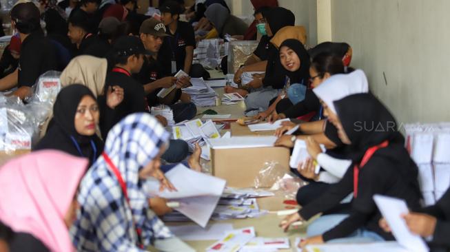 Petugas melipat surat suara di Gudang logistik KPU Komplek Pergudangan Zoodia, Jakarta, Minggu (17/2). [Suara.com/Muhaimin A Untung]