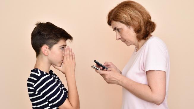 Orangtua tengah mengecek ponsel milik anak. Sebagai ilustrasi [Shutterstock].