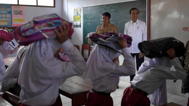 Presiden Joko Widodo (kanan) meninjau simulasi terjadinya gempa bumi saat menghadiri Program Tagana Masuk Sekolah dan Kampung Siaga Bencana di SDN Panimbang Jaya 1, Pandeglang, Banten, Senin (18/2). ANTARA FOTO/Puspa Perwitasari