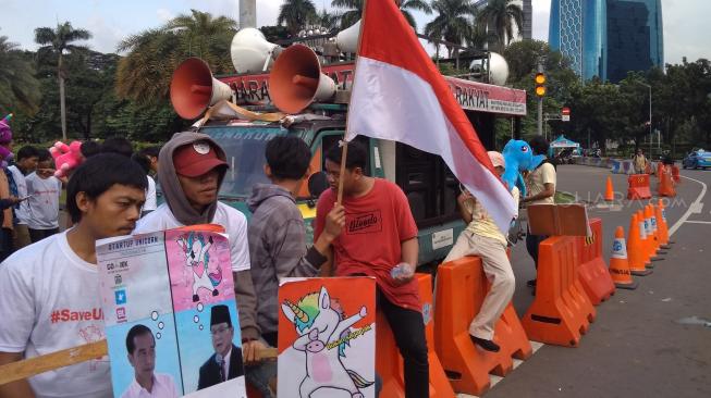 Puluhan pemuda yang mengatasnamakan diri sebagai Komunitas Bloger Milenial melakukan aksi damai di dekat kawasan Monas terkait Unicorn yang disinggung di debat Capres kedua. (Suara.com/Fakhri Fuad)